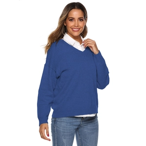 Close-up of blue V-neck knit sweater with ribbed cuffs and loose fit over a white shirt