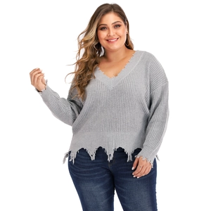 Detailed close-up of distressed ripped edges on a grey V-neck oversized knit sweater