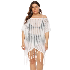 Detail of white crochet beach cover-up featuring vertical hollow stripes and fringe hem