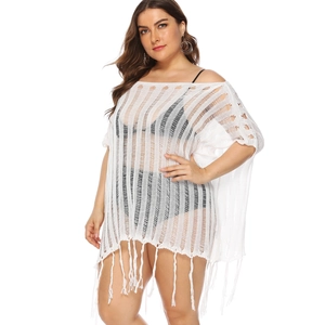 Detail of white crochet beach cover-up featuring vertical cut-outs and long fringe hem
