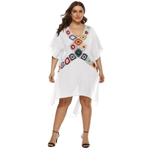 Detail of vibrant handmade crochet floral patchwork on a white V-neck beach cover-up dress