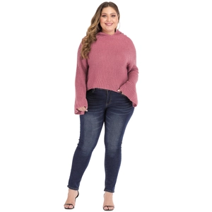 Plus size pink hooded sweater with flare sleeves and dark blue skinny jeans on white background