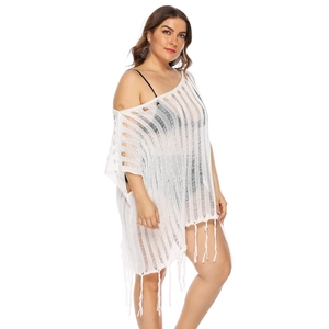 Detailed view of white crochet beach cover-up featuring hollow texture and fringe tassels
