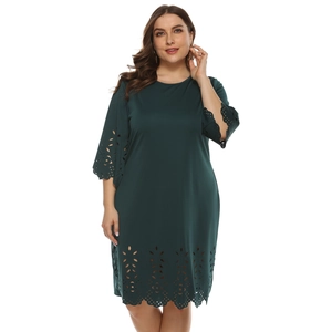 Detail of dark green dress showing laser-cut floral patterns on sleeves and hemline