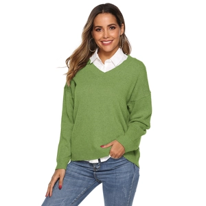 Detail of green V-neck knitted sweater layered with white shirt and blue denim jeans