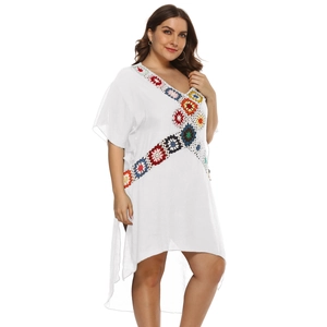 Detail of colorful handmade crochet flowers on a white V-neck boho beach dress