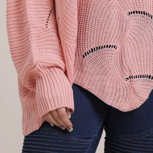 Detail of pink knitted sweater showing intricate openwork patterns and ribbed cuffs texture
