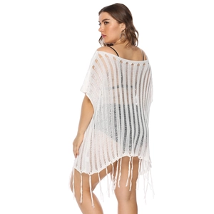 Detail of white crochet beach cover-up featuring hollow-out knit and long fringe tassels