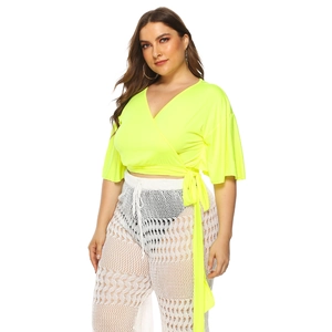 Detail of neon yellow wrap top with V-neckline and white hollow lace crochet pants