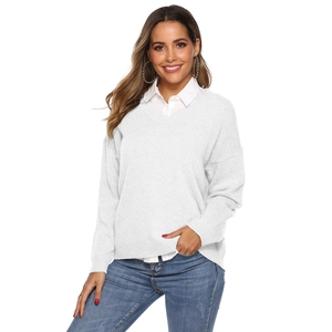 Detail of white V-neck knit sweater layered with shirt and casual denim jeans