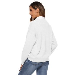Detail view of white knit sweater showing dropped shoulder design and ribbed cuffs texture