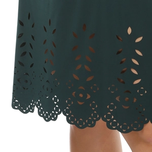 Detailed view of dark green dress hem featuring laser-cut floral patterns and scalloped edges