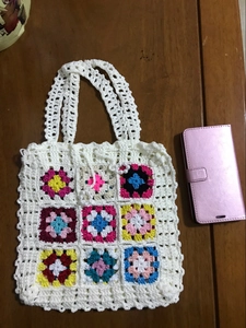 Détail du sac au crochet avec carrés multicolores et accents de perles sur la poignée