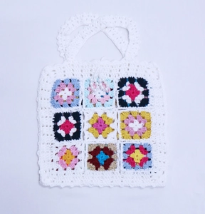 Détail de motifs de carrés crochetés colorés et décor de perles sur le sac à main blanc