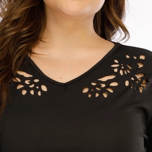 Détail du col en V avec des motifs floraux découpés au laser sur un tissu noir