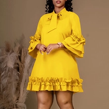 Detailed view of yellow dress with ruffled layers and delicate neckline bow tie