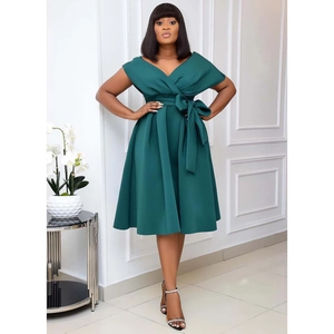 Detail of elegant dark green dress featuring a large waist bow and pleated A-line skirt