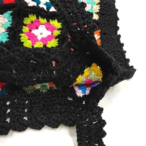 Détail des motifs crochetés granny square colorés sur un sac à main noir tricoté