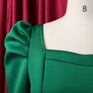 Detail von quadratischem Ausschnitt und Puffärmeln an einem smaragdgrünen Kleid
