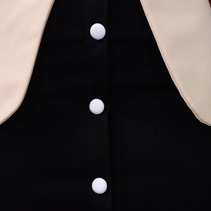 Détail d'une robe élégante avec panneaux contrastés et boutons recouverts de tissu blanc