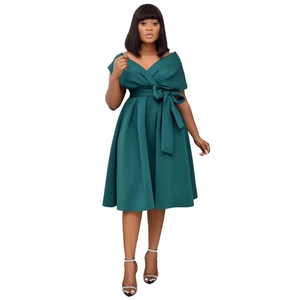 Detail of elegant V-neck pleated dress featuring a large bow waist tie in dark green fabric