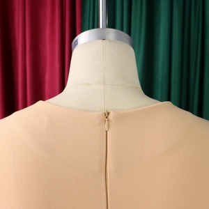 Detail of an apricot square neck dress featuring a hidden zipper back closure on a mannequin