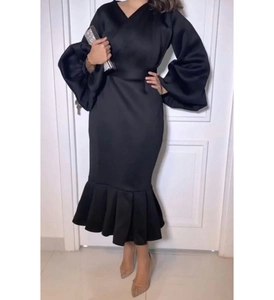 Detail view of the elegant black V-neck puff sleeves and fish-tail hem on this formal dress