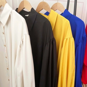 Detail of puff sleeves and gold metal buttons on colorful loose-fit shirt dresses