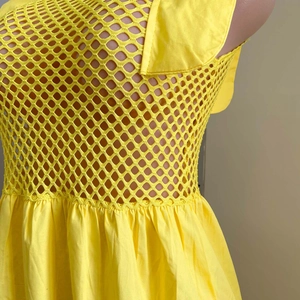 Détail de la robe jaune montrant la texture en maille, la taille froncée et le tissu lisse