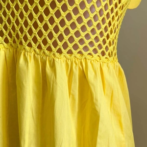 Gros plan du corsage en crochet jaune et détails de taille plissée de la jupe