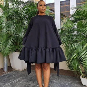 Detail view of the black oversized puff sleeve dress with a ruffled pleated hemline style