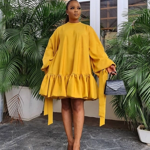 Mustard yellow loose dress with puff sleeves and ruffled hem in an outdoor garden setting