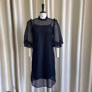 Detail of black mesh dress featuring hollow-out patterns and elegant puff sleeves