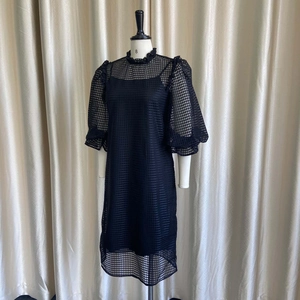 Detail of black puff sleeve dress with mesh overlay and ruffle collar on mannequin