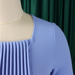 Close-up of light blue dress featuring a square neckline and pleated bodice detail