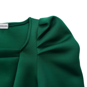 Makroaufnahme von dunkelgrünem Kleid mit Karree-Ausschnitt, Puffärmeln und Markenetikett