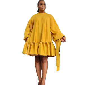 Close-up of bright yellow mini dress with balloon sleeves, ribbon ties and ruffled hem