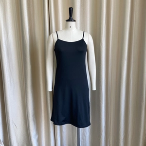 Detail of a black slip dress with thin straps and smooth elastic fabric on a mannequin