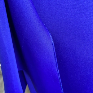 Macro du tissu satiné bleu roi et des coutures précises sur l'ourlet de la robe