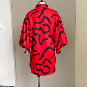 Detail of red and black abstract print dress featuring puff sleeves and button collar