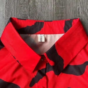 Close-up of printed shirt collar with SISOH brand label on vibrant red abstract pattern