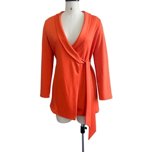 Detailed view of bright orange V-neck wrap romper with side tie and pleated waist design