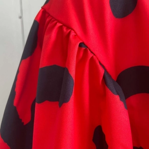Detailed view of red fabric with black polka dots featuring pleated ruffled layers