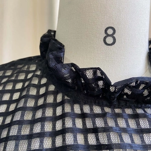 Detailed view of black mesh fabric dress with ruffled collar and puff sleeve texture