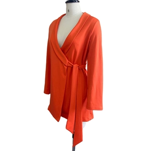 Detailed close-up of a bright orange long-sleeve wrap dress with tie-waist and V-neckline