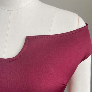 Détail de l'encolure dénudée bordeaux avec coutures fines sur la robe taille haute