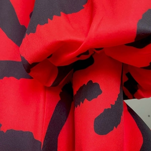 Macro detail of red and black abstract leopard print fabric with voluminous pleated texture