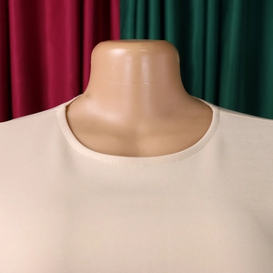 Détail du col rond et de la texture du tissu de la robe en tricot beige sur un mannequin
