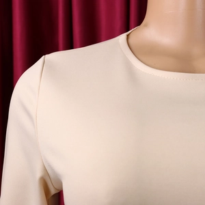 Détail d'une robe beige élégante avec col rond et texture de maille fine et douce