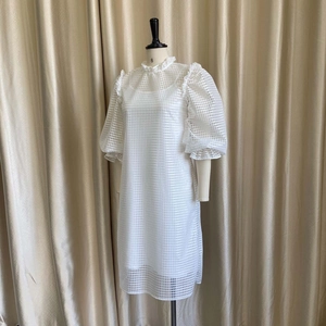 Detailed view of white puff sleeve dress featuring hollow-out lattice fabric and ruffled collar